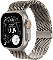Eine detaillierte Produktaufnahme der Apple Watch Ultra 3 mit dem robusten Titan-Gehäuse und dem einzigartigen, dunklen Titan-Milanese-Mesh-Armband. Das Zifferblatt zeigt eine komplexe, technische Anzeige mit mehreren Komplikationen. Das Gerät wird in einer sauberen, studioartigen Umgebung präsentiert, die die hochwertigen Materialien und das markante Design hervorhebt, das für extreme Leistung und Luxus steht.