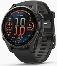 Ein Nahaufnahme-Foto der Garmin Fenix 8 Smartwatch, das das Premium-Stahl- oder Titangehäuse und das strapazierfähige schwarze Silikon-Taktikarmband zeigt. Das AMOLED-Display ist aktiviert und präsentiert ein funktionales, multisportliches Zifferblatt mit einer analogen Uhrzeitanzeige und wichtigen Leistungsdaten. Das Design ist robust und kommuniziert deutsche Ingenieurskunst für Outdoor-Abenteuer und professionelles Training.